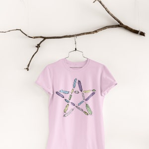 May include: A pink t-shirt with a five-pointed star design featuring a colorful crystal pattern.