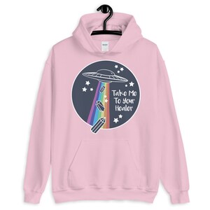 May include: Pink hoodie with a graphic of a UFO with a rainbow trail of crystals and the text "Take Me To Your Healer".