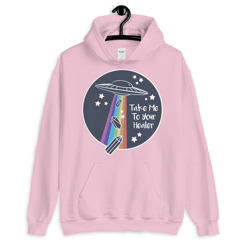 May include: Pink hoodie with a graphic of a UFO with a rainbow trail of crystals and the text "Take Me To Your Healer".