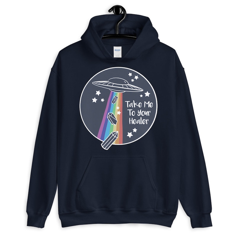 May include: Navy blue hoodie with a white graphic of a UFO, rainbow, and crystals. The text "Take Me To Your Healer" is printed on the graphic.