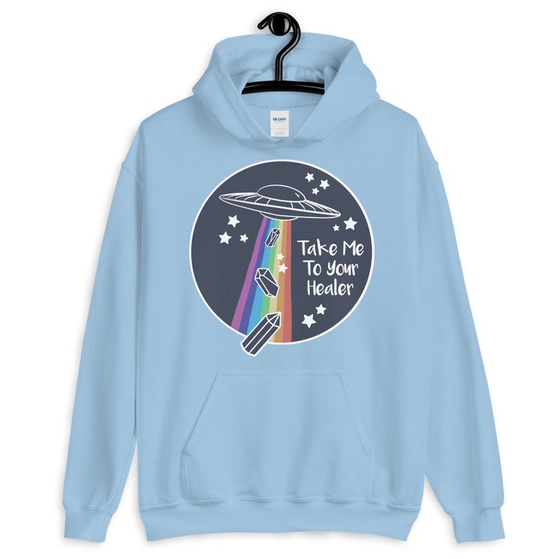 May include: Light blue hoodie with a graphic of a UFO, rainbow crystals, and the text "Take Me To Your Healer" on a dark blue circle.