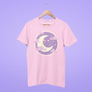 May include: A pink t-shirt with a purple and yellow crescent moon and clouds graphic.