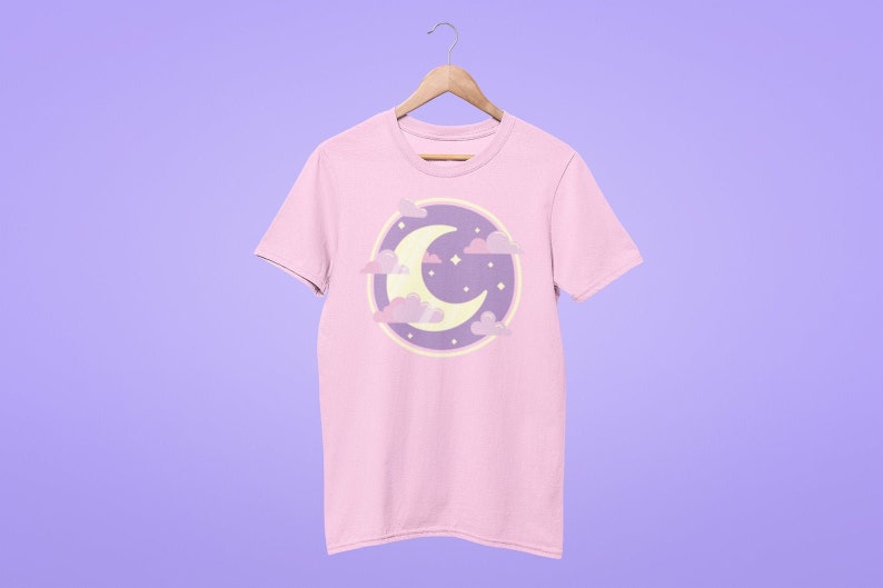 May include: A pink t-shirt with a purple and yellow crescent moon and clouds graphic.