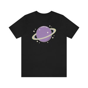 K&ouml;nnte beinhalten: Ein schwarzes T-Shirt mit einem lila Planeten mit einem Regenbogenring darum. Der Planet ist von kleinen wei&szlig;en Sternen umgeben.