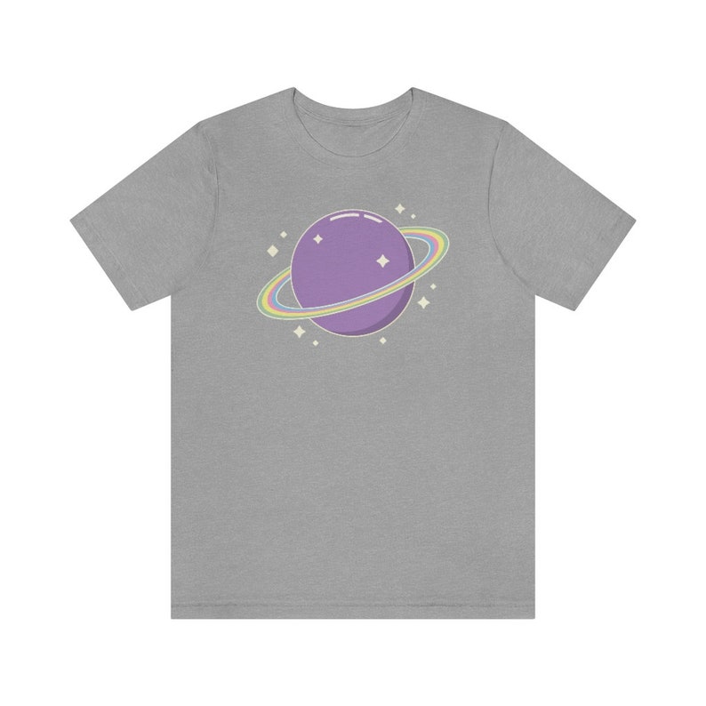 K&ouml;nnte beinhalten: Ein graues T-Shirt mit einem lila Planeten mit einem Regenbogenring darum. Der Planet hat ein paar wei&szlig;e Sterne drumherum.
