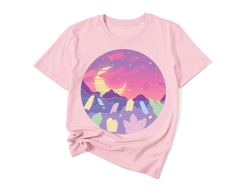 May include: Pink short-sleeved t-shirt with a graphic print of a crescent moon and a landscape with mountains and crystals in a circle.