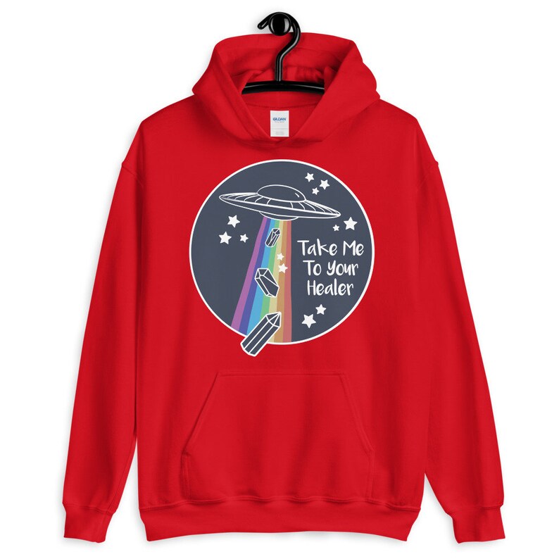 May include: Red hooded sweatshirt with a graphic of a UFO flying over a rainbow and crystals. The text "Take Me To Your Healer" is printed on the graphic.