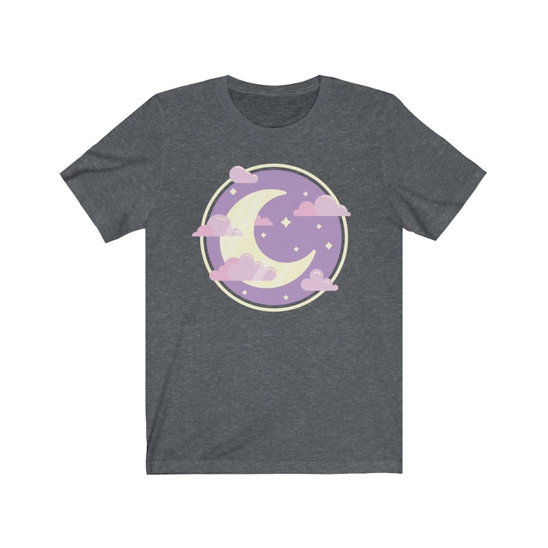 May include: A dark heather grey t-shirt with a purple circle design featuring a crescent moon and pink clouds. The moon is yellow and there are small white stars in the circle.