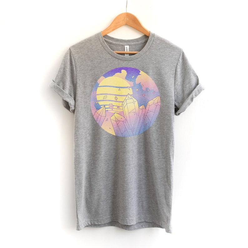 May include: A heather grey t-shirt with a circular graphic of a sunset with crystals and a purple, pink, and yellow gradient.