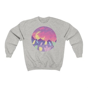 May include: A gray sweatshirt with a circular graphic design featuring a crescent moon, stars, and a pink and purple landscape with colorful crystals.