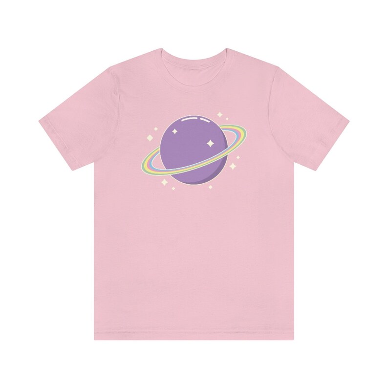 K&ouml;nnte beinhalten: Ein pinkfarbenes T-Shirt mit einem lila Planeten mit einem Regenbogenring und wei&szlig;en Sternen.