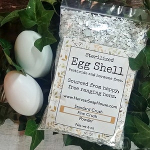 May include: A white bag of sterilized egg shell powder, sourced from happy, free-range hens. The bag is labeled "Sterilized Egg Shell", "Pesticide and hormone free", "Sourced from happy, free ranging hens", "www.HarvestSoapHouse.com", "Standard Crush", "Fine Crush", "Powder", and "Net wt 6 oz".