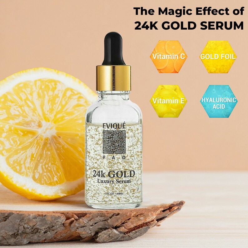 May include: A clear glass bottle with a gold cap and label. The bottle contains a gold serum with gold flakes. The label reads "EVIQU&Eacute; 24k GOLD Luxury Serum". The bottle is sitting on a wooden surface. The image also includes four hexagonal shapes with text: "Vitamin C", "Gold Foil", "Vitamin E", and "Hyaluronic Acid".