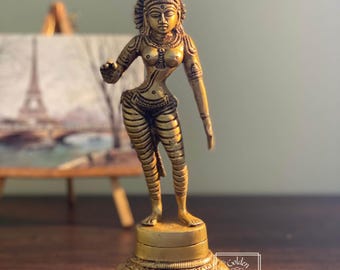 Puede incluir: Una estatua de metal dorado de una deidad femenina con una corona y detalles intrincados. La estatua está de pie sobre una base en forma de loto.