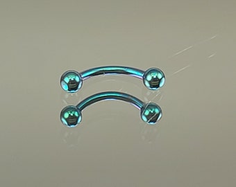 Può includere: Due pezzi di gioielleria per il corpo a forma di barra di colore blu turchese con estremità arrotondate. I gioielli sono in acciaio chirurgico.