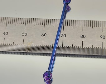 May include: A blue titanium barbell with purple gem ends, measuring approximately 7 cm in length.
