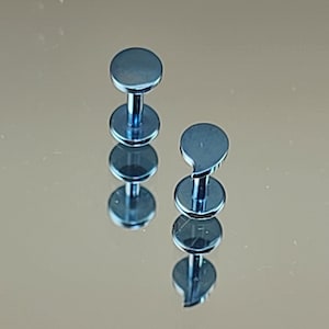 May include: Two blue titanium body jewelry pieces. One is a round stud and the other is a teardrop shaped stud.