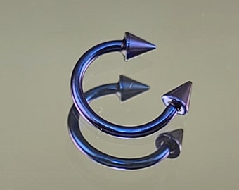 May include: Two blue and purple metal circular body piercing rings with pointed ends.