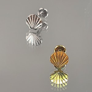 May include: Three pairs of gold and silver seashell stud earrings. The earrings are small and delicate, with a simple design.