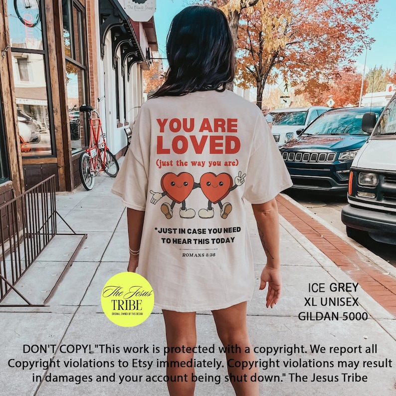 K&ouml;nnte beinhalten: Wei&szlig;es T-Shirt mit einem roten Herz-Motiv und dem Text "You are Loved (just the way you are)". Das Shirt hat au&szlig;erdem den Text "Just in case you need to hear this today" und "Romans 8:28". Das Shirt ist in Eisgrau, XL Unisex, Gildan 5000 erh&auml;ltlich.