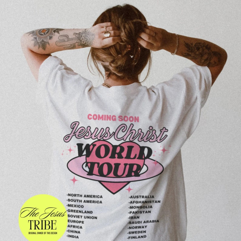 Puede incluir: Camiseta blanca con un gr&aacute;fico de coraz&oacute;n rosa y el texto "Jesus Christ World Tour" en una fuente retro. El texto "Coming Soon" est&aacute; por encima del gr&aacute;fico. La camiseta tambi&eacute;n tiene una lista de pa&iacute;ses impresos en ella.