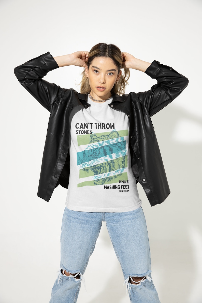 May include: White t-shirt with a graphic of a tiger's face and the text "Can't Throw Stones While Washing Feet John 13:14".