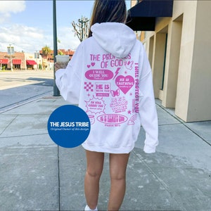 May include: White hoodie with pink graphic text on the back. The text includes phrases like "The Promises of God," "I Will Guide You," and "He Is Faithful." The hoodie also features a blue circle with the text "THE JESUS TRIBE."