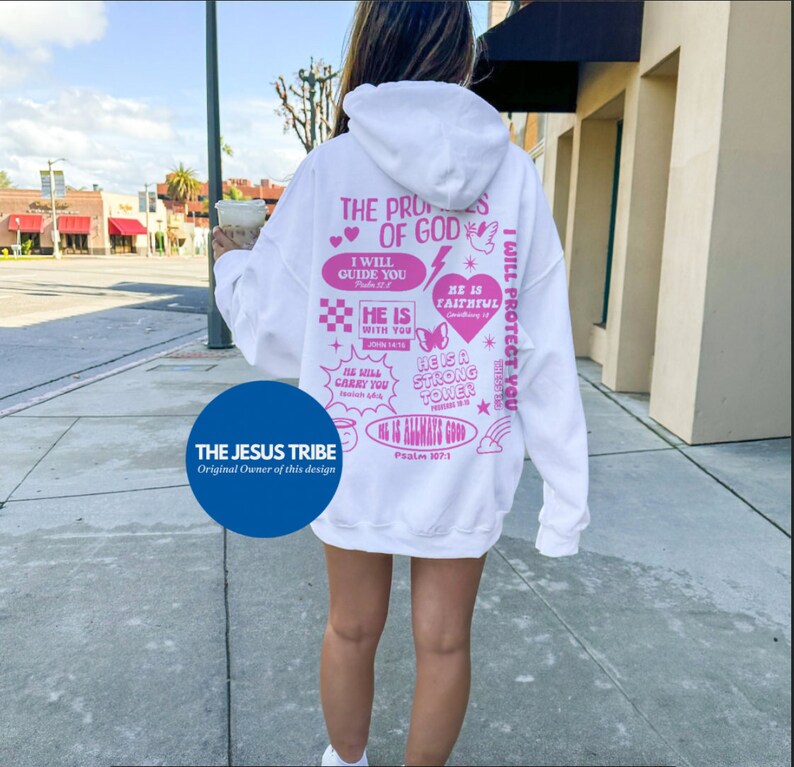 May include: White hoodie with pink graphic text on the back. The text includes phrases like "The Promises of God," "I Will Guide You," and "He Is Faithful." The hoodie also features a blue circle with the text "THE JESUS TRIBE."