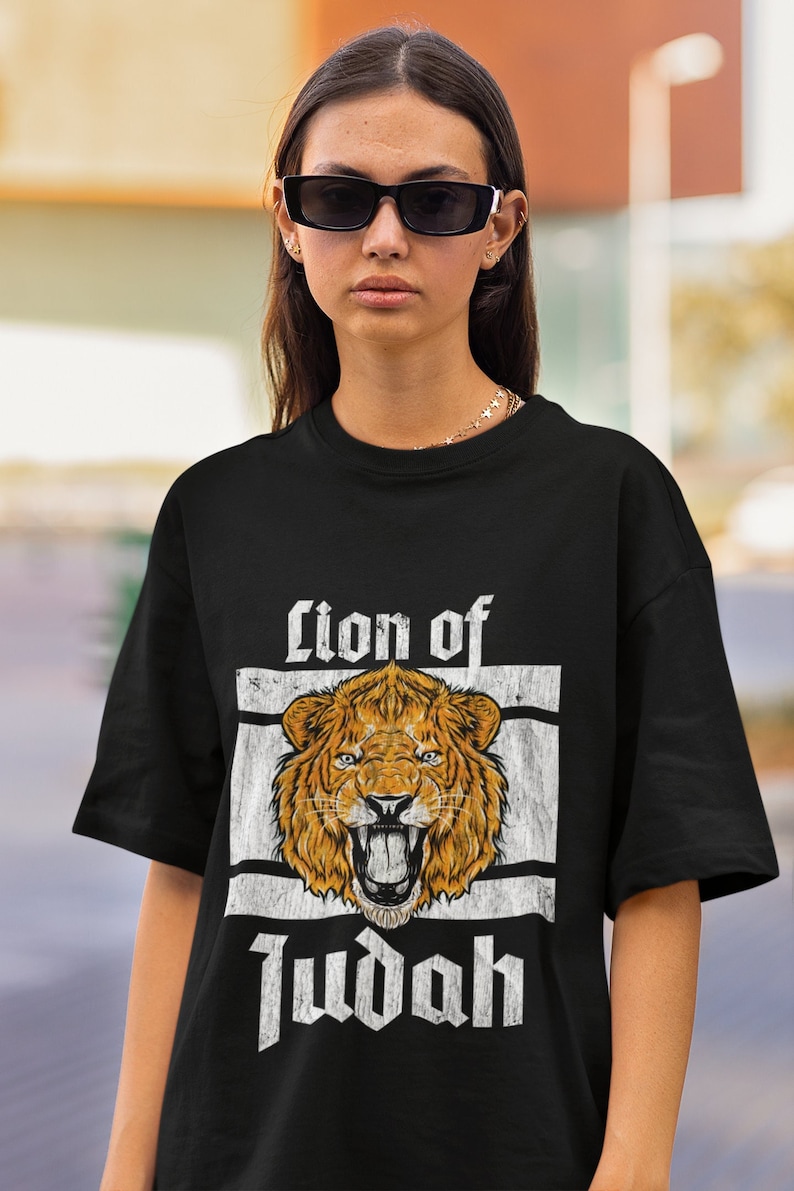 May include: Black t-shirt featuring a distressed graphic of a roaring lion's head with the text "Lion of Judah" in a vintage style. The design is centered on the shirt, creating a bold statement. The shirt is a classic crew neck.