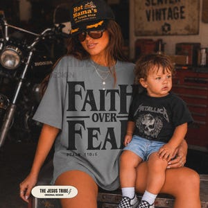 Op de afbeelding: Een grijs t-shirt met de zwarte tekst FAITH OVER FEAR en PSALM 118:6, gecombineerd met een zwarte baseballpet met gele tekst Hot Mama's #1 Truck Stop, en een zwart t-shirt met een Metallica schedelafbeelding en een blauwe spijkerbroekshort.