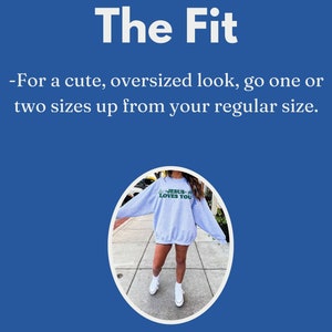 May include: A light gray sweatshirt with the text "JESUS LOVES YOU" in green. The image includes the text "The Fit" and instructions to size up for an oversized look. The model is wearing white sneakers.
