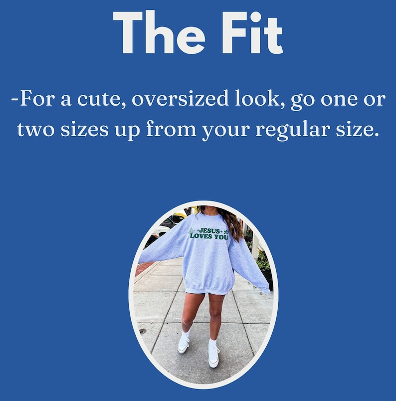 May include: A light gray sweatshirt with the text "JESUS LOVES YOU" in green. The image includes the text "The Fit" and instructions to size up for an oversized look. The model is wearing white sneakers.