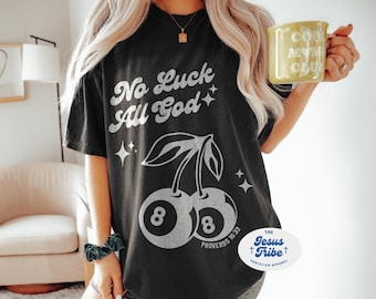 Puede incluir: Camiseta negra con texto blanco que dice "No Luck All God" y un gráfico de dos cerezas con el número 8 en cada una. Las cerezas están estilizadas para parecer bolas de billar. El texto "Proverbs 16:33" está debajo de las cerezas. La camiseta también tiene una etiqueta blanca con el texto "THE Jesus Tribe CHRISTIAN APPAREL".