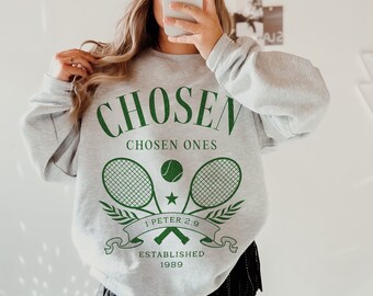 May include: Gray sweatshirt with a green graphic design that says "CHOSEN" and "CHOSEN ONES" with two tennis rackets and a tennis ball. The graphic also includes the text "1 PETER 2:9" and "ESTABLISHED 1989".