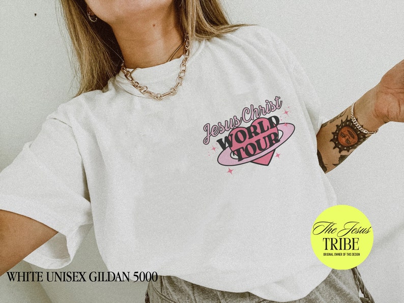 Puede incluir: Camiseta blanca unisex Gildan 5000 con un gr&aacute;fico de coraz&oacute;n rosa y el texto "Jesus Christ World Tour".