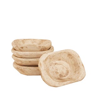 Op de afbeelding: Een stapel van vier kleine, vierkante kommen met afgeronde hoeken en een lichtbeige, verweerde, getextureerde afwerking. De kommen hebben een rustiek, onregelmatig uiterlijk met donkerbruine vlekken over het lichtbruine materiaal.