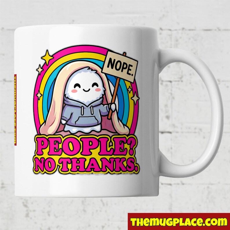 Op de afbeelding: Witte keramische mok met een cartoon spookje met een bordje met de tekst "NOPE". Het spookje staat in een regenboog met de tekst "PEOPLE? NO THANKS." De mok heeft een wit handvat en de tekst "TheMugPlace.com" onderaan.