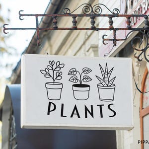 May include: A white sign with black line drawings of three potted plants and the word "PLANTS" in black lettering. The sign is hanging from a rusty metal bracket.
