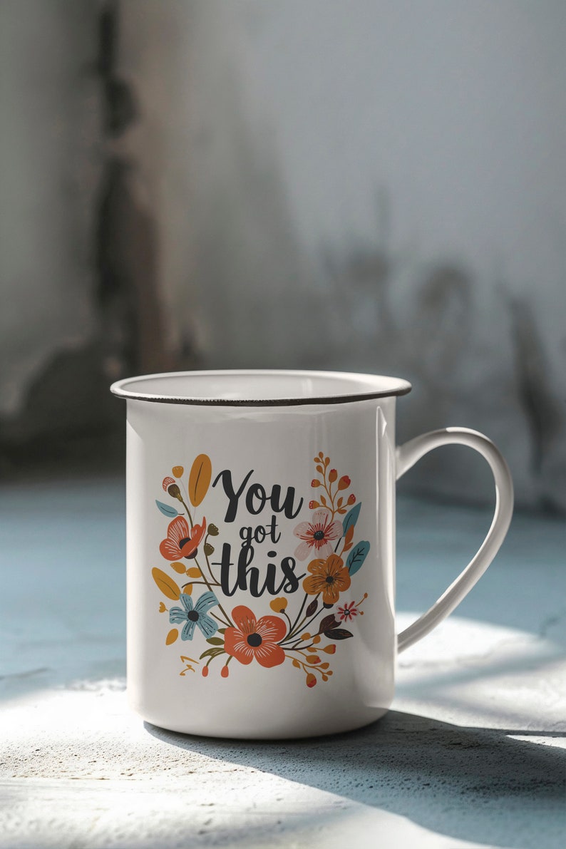 May include: White enamel mug with a black rim and handle. The mug has a floral design and the text "You got this" in black.