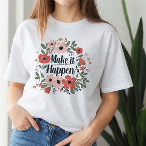 May include: White t-shirt with a floral design and the text "Make it Happen'" printed on the front.