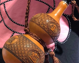 May include: A brown gourd bottle with intricate carvings and a brown tassel. The bottle is decorated with Chinese characters and geometric patterns.