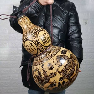 May include: A brown gourd bottle with a black strap and intricate black designs. The bottle features Chinese characters and a dragon and phoenix design.