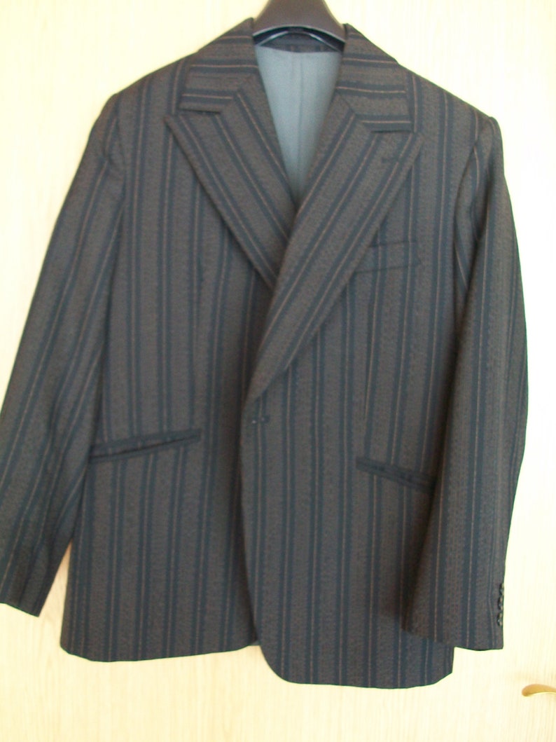 May include: A striped blazer with a dark brown and black color scheme. The blazer has a single button closure and a notched lapel.