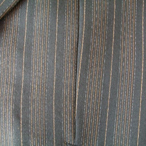 May include: Close-up of a dark gray fabric with thin, vertical stripes of a lighter gray and brown color.