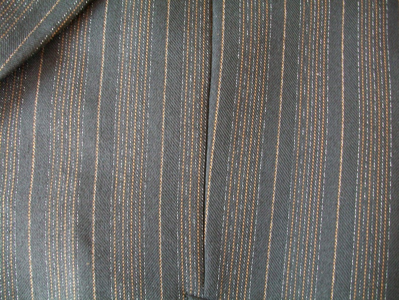 May include: Close-up of a dark gray fabric with thin, vertical stripes of a lighter gray and brown color.