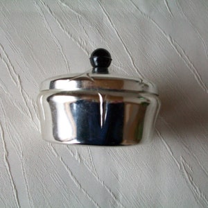 Small silver-colored round box made of metal - for decoration or for storing small objects.