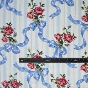 May include: Fabric with a repeating pattern of red roses, light blue ribbons, and green leaves on a white and light blue striped background. The fabric is suitable for sewing projects and crafts.