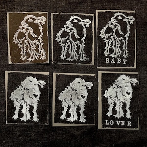 May include: Six white ink stamps on a dark gray background. Each stamp features a stylized image of a dog with the words "BABY" and "LOVE" printed below the images.