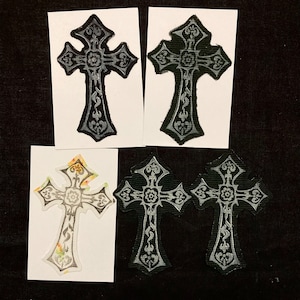 Könnte beinhalten: Vier Bügelbilder mit einem silbernen Kreuz mit verzierten Details auf schwarzem Hintergrund. Die Kreuze werden auf weißem Karton gezeigt.