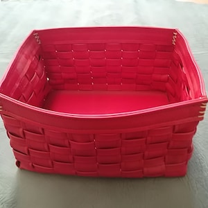 May include: A bright pink woven storage basket with a rectangular shape. The basket is made of a woven material that is similar to leather.